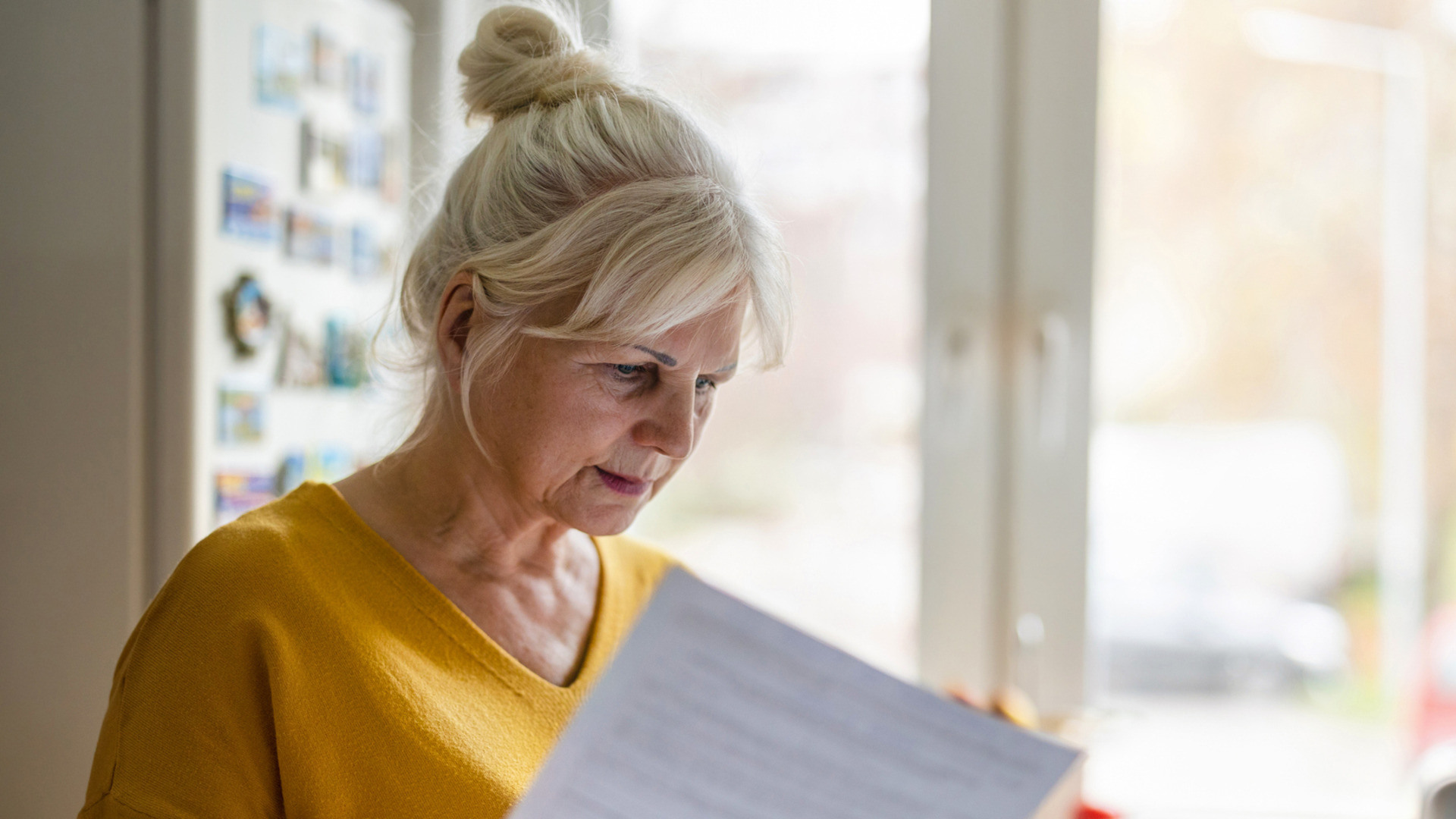 Eldre kvinne leser veldig nøye på noen papirer hun har fremfor seg