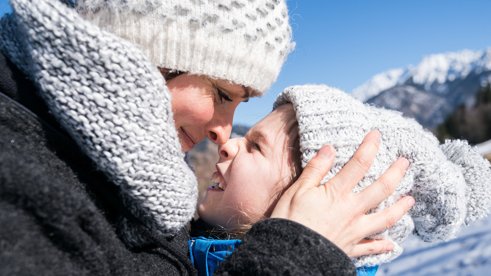 Mor holder et barn ca 8 år mellom på hodet og nesene deres møtes