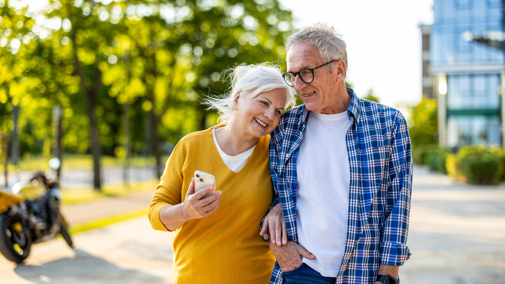 Eldre par lener seg mot hverandre mens de går tur i solen.